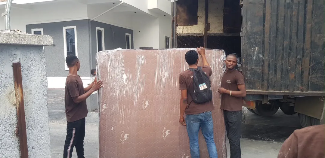 Shalom Relocation crew handling furniture beside a loaded moving truck